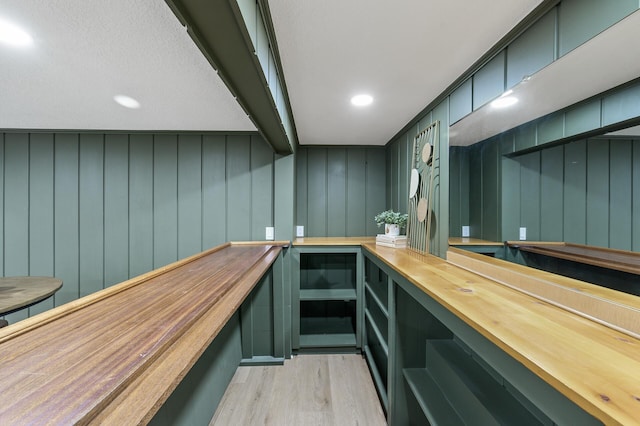 bar featuring light wood-type flooring, beam ceiling, and wet bar