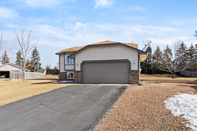 view of front of home featuring brick siding, aphalt driveway, and fence