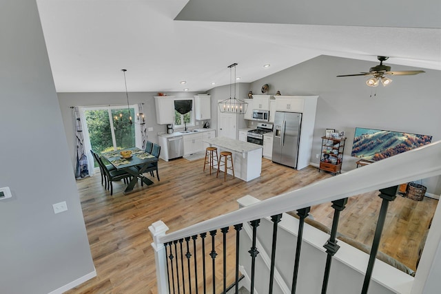 interior space with a kitchen island, white cabinetry, stainless steel appliances, and pendant lighting