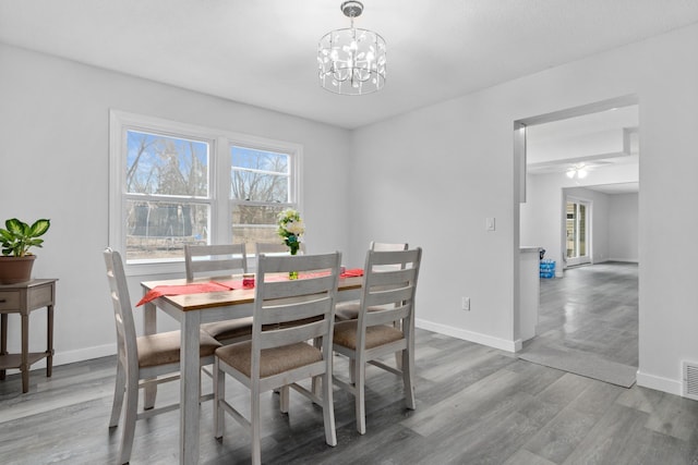 dining space with a notable chandelier, visible vents, baseboards, and wood finished floors