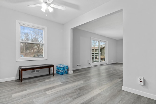 unfurnished room featuring a ceiling fan, visible vents, baseboards, and wood finished floors