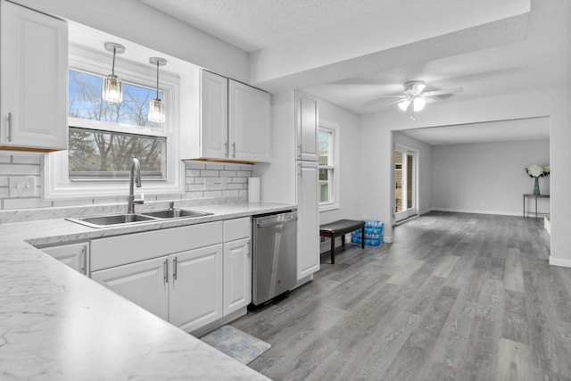 kitchen featuring decorative backsplash, stainless steel dishwasher, a healthy amount of sunlight, white cabinetry, and a sink