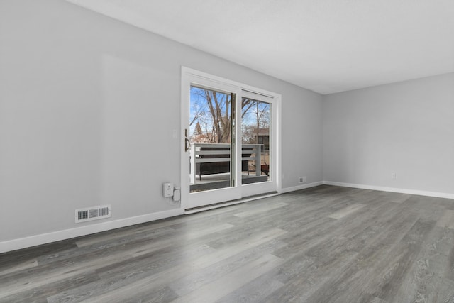 unfurnished room featuring visible vents, baseboards, and wood finished floors