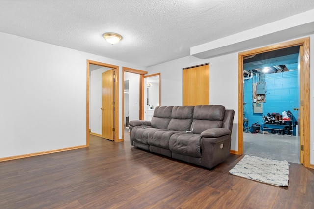 living area featuring a textured ceiling, wood finished floors, concrete block wall, and baseboards