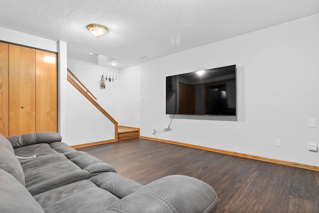 living room featuring a textured ceiling, wood finished floors, stairs, and baseboards