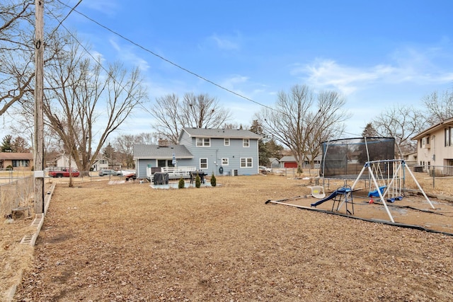 back of house with a trampoline, a playground, fence, and a chimney