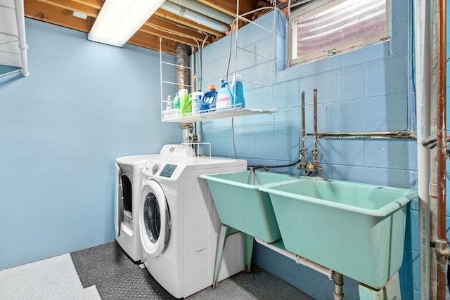 clothes washing area featuring concrete block wall, laundry area, and washer and clothes dryer