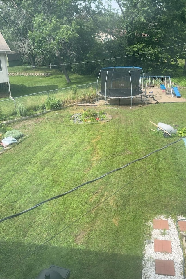 view of yard featuring a trampoline, fence, and a playground