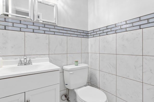 bathroom with tile walls, vanity, and toilet