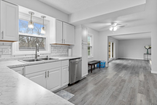 kitchen featuring a sink, stainless steel dishwasher, white cabinetry, light countertops, and a textured ceiling