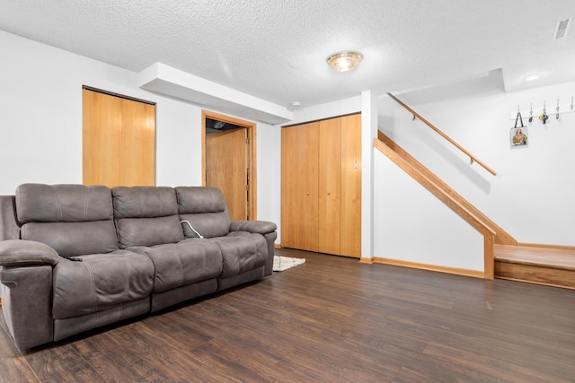 living area featuring wood finished floors, stairs, a textured ceiling, and baseboards