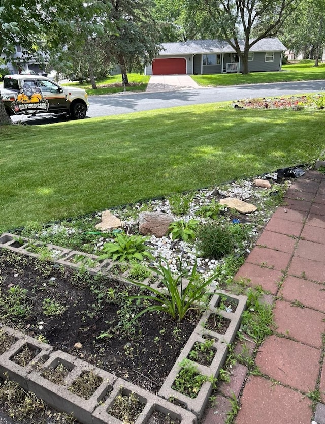 view of green lawn featuring a garage and asphalt driveway