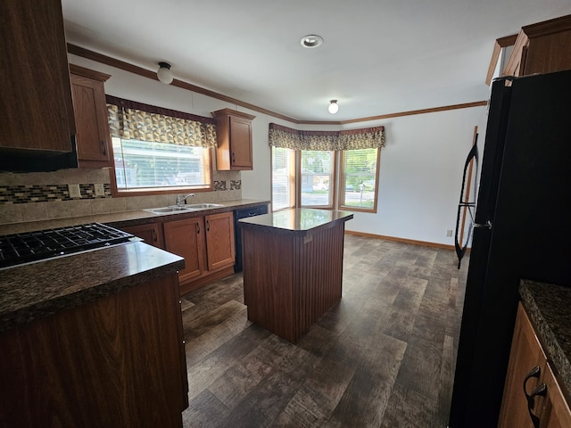 kitchen featuring a healthy amount of sunlight, a center island, black appliances, tasteful backsplash, and dark countertops