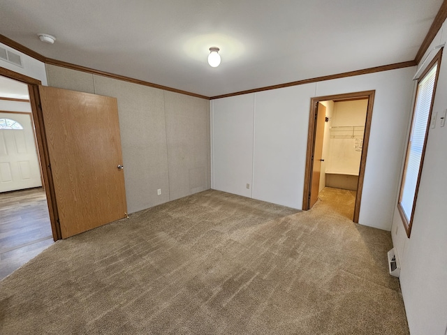 unfurnished bedroom with visible vents, multiple windows, light colored carpet, and crown molding