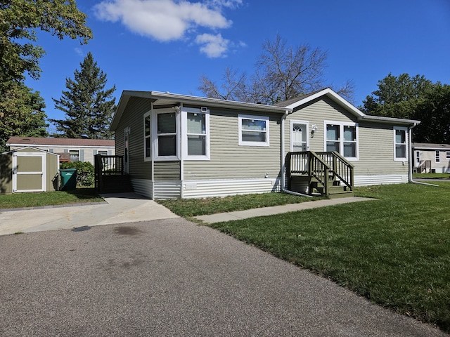 manufactured / mobile home with a storage shed, a front yard, and an outbuilding