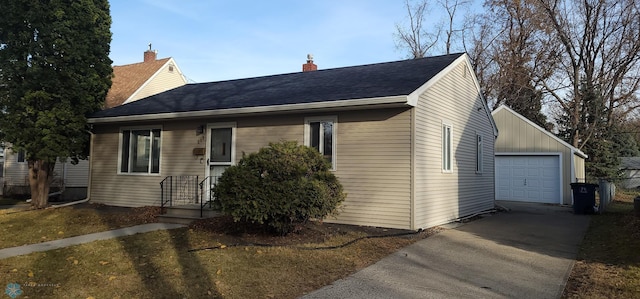 view of front of property featuring an outbuilding, roof with shingles, a chimney, and a garage