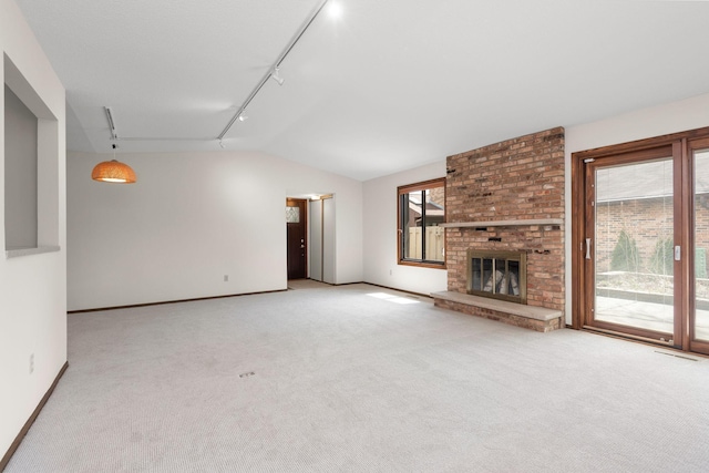 1021 Yuma Ln N, Plymouth, MN 55447 - unfurnished living room featuring track lighting, plenty of natural light, carpet flooring, lofted ceiling, and a brick fireplace