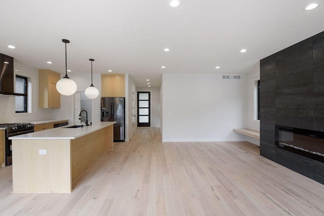 kitchen featuring visible vents, light brown cabinetry, a sink, ventilation hood, and black appliances