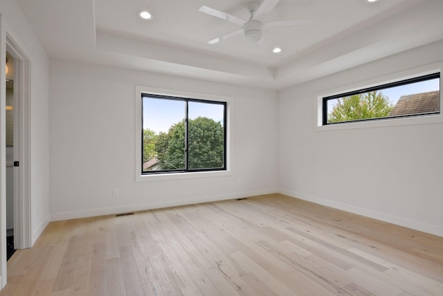 unfurnished room featuring recessed lighting, visible vents, baseboards, a tray ceiling, and light wood finished floors