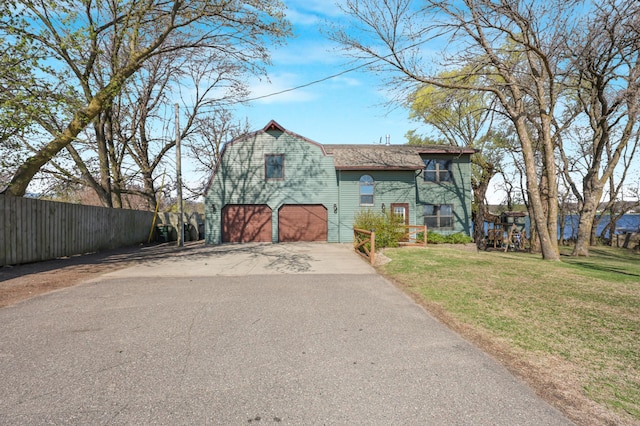 view of front of house featuring aphalt driveway, fence, a front yard, a barn, and an attached garage