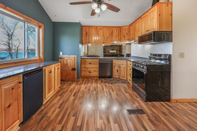 kitchen featuring dark countertops, a ceiling fan, wood finished floors, tasteful backsplash, and black appliances