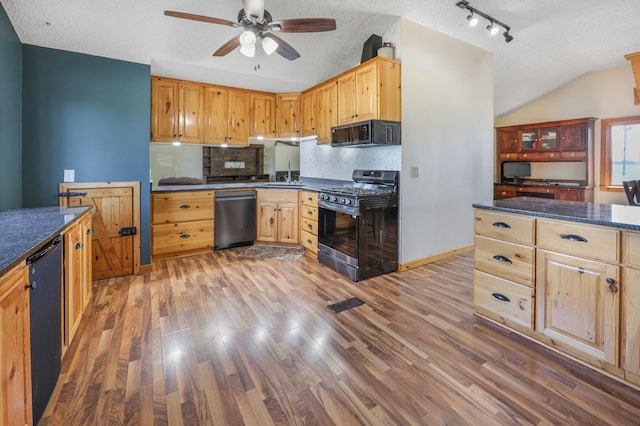 kitchen featuring dark countertops, a ceiling fan, stainless steel appliances, and wood finished floors
