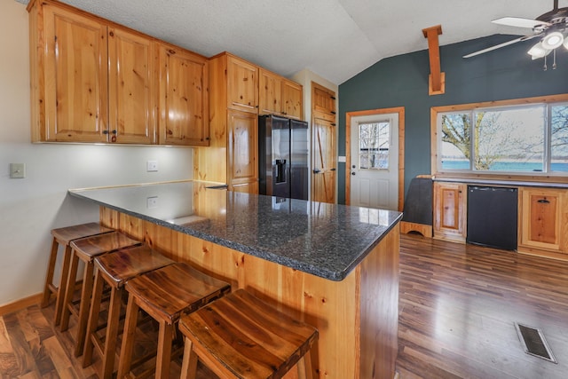 kitchen featuring visible vents, baseboards, vaulted ceiling, and fridge with ice dispenser