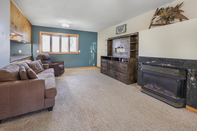 living room with a textured ceiling, a glass covered fireplace, baseboards, and carpet