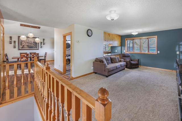 living room featuring carpet floors, a textured ceiling, stacked washer / drying machine, and baseboards