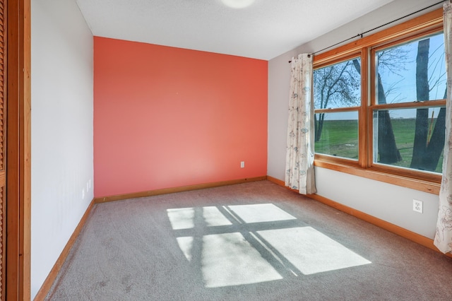 carpeted spare room featuring baseboards