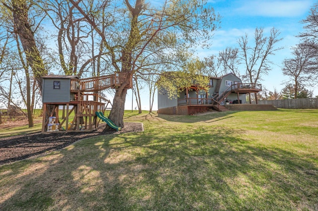 view of yard with a deck, fence, and a playground