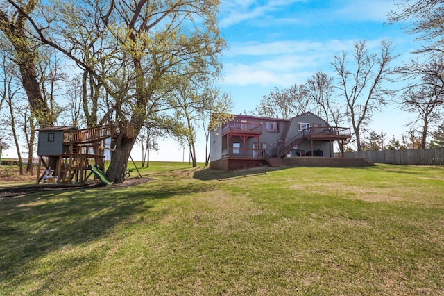view of yard with a playground, fence, a wooden deck, and stairs