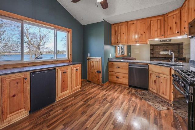 kitchen with lofted ceiling, dark countertops, a sink, dishwasher, and black gas range oven
