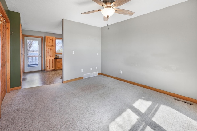 carpeted spare room with a ceiling fan, baseboards, and visible vents