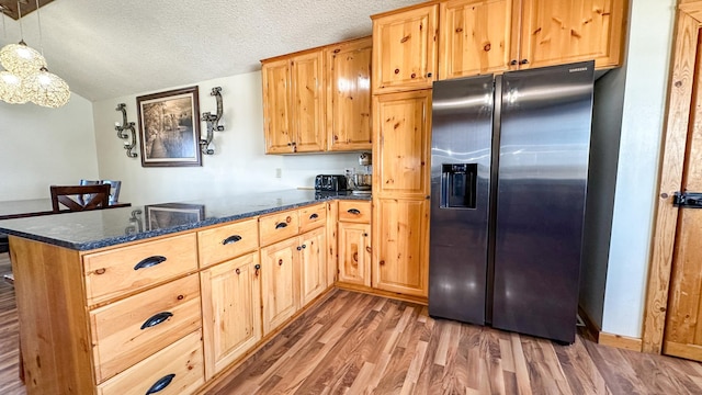kitchen with a textured ceiling, light wood-style flooring, dark stone counters, a peninsula, and stainless steel refrigerator with ice dispenser