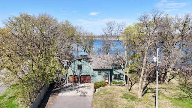 view of front of home featuring concrete driveway, an attached garage, a shingled roof, and a front lawn