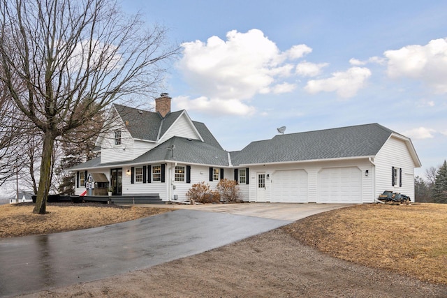 view of front of property with a chimney, a shingled roof, concrete driveway, covered porch, and a garage