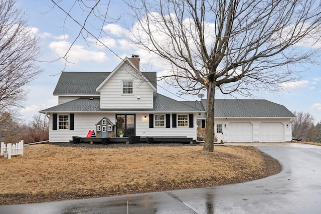 view of front of property featuring driveway, an attached garage, a chimney, and roof with shingles