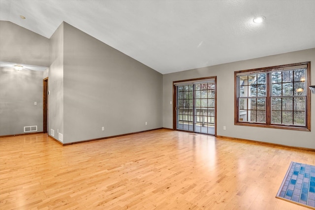 spare room with lofted ceiling, light wood finished floors, baseboards, and visible vents