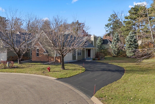 view of front of property featuring aphalt driveway, brick siding, a chimney, a garage, and a front lawn