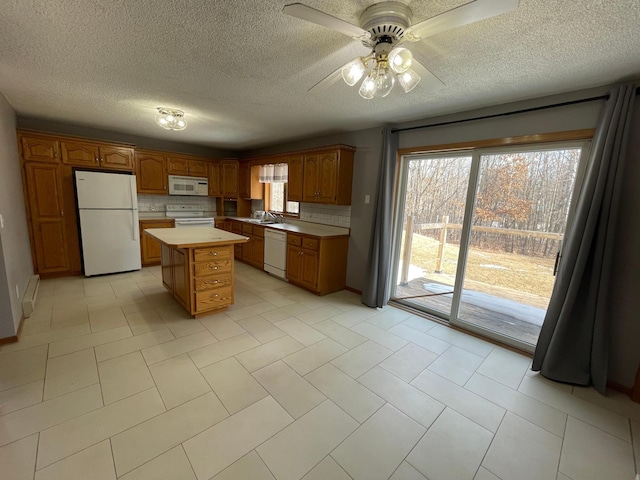 kitchen featuring white appliances, tasteful backsplash, brown cabinets, a center island, and light countertops