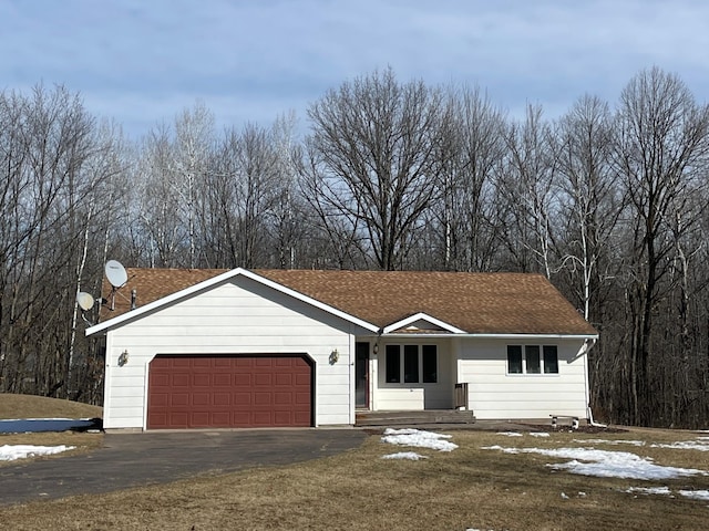 ranch-style home with a garage and aphalt driveway