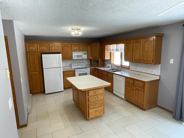 kitchen featuring brown cabinets, white appliances, light countertops, and a sink