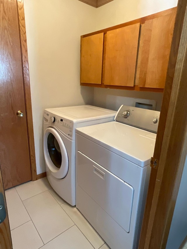 laundry area featuring light tile patterned floors, independent washer and dryer, and cabinet space