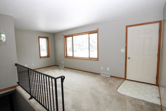 interior space featuring light carpet, baseboards, and visible vents