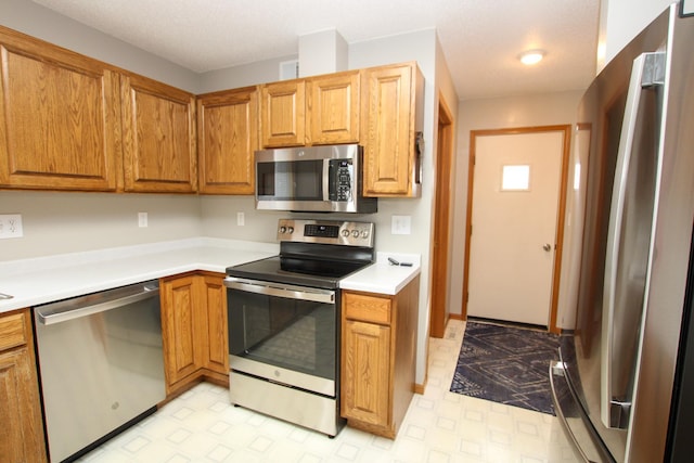 kitchen with brown cabinets, light floors, stainless steel appliances, and light countertops