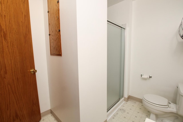 bathroom featuring toilet, a stall shower, baseboards, and tile patterned floors