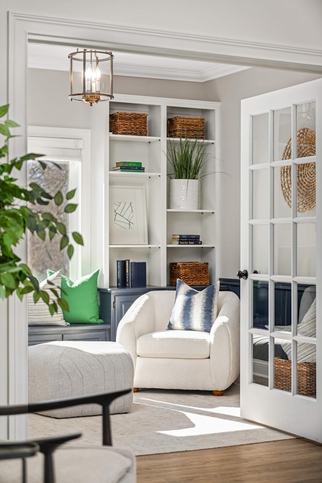 living area featuring a chandelier, wood finished floors, and crown molding