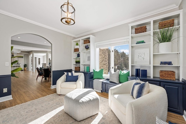 living room with crown molding, arched walkways, and wood finished floors