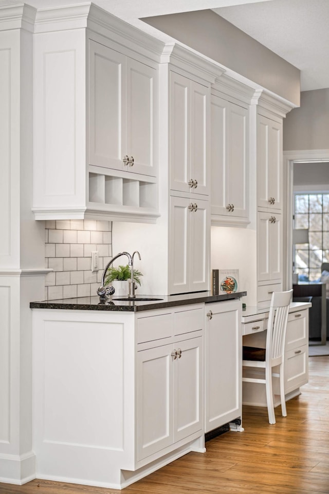 bar with light wood-style floors, backsplash, and a sink